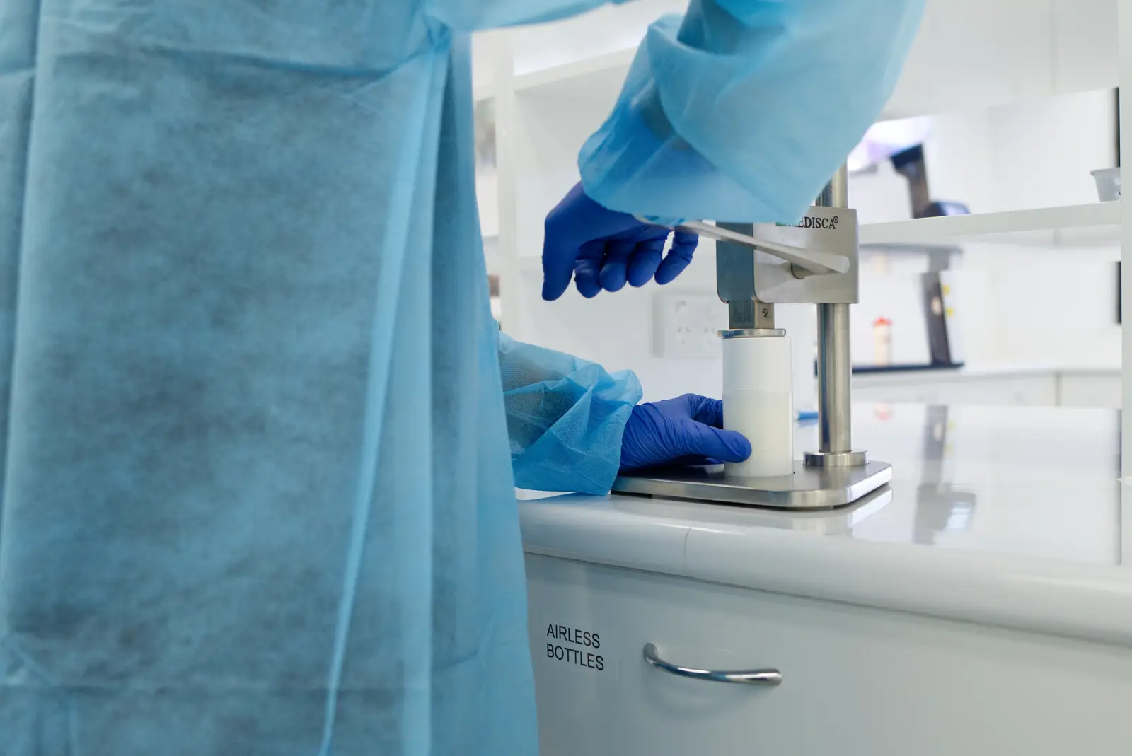 Pharmacist in a lab gown preparing a compounded cream at an ointment mill
